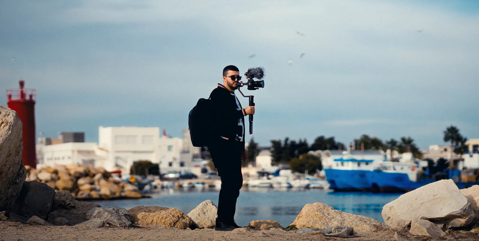 A man photographing at Béni Khiar harbor, Tunisia with a gimbal and microphone.